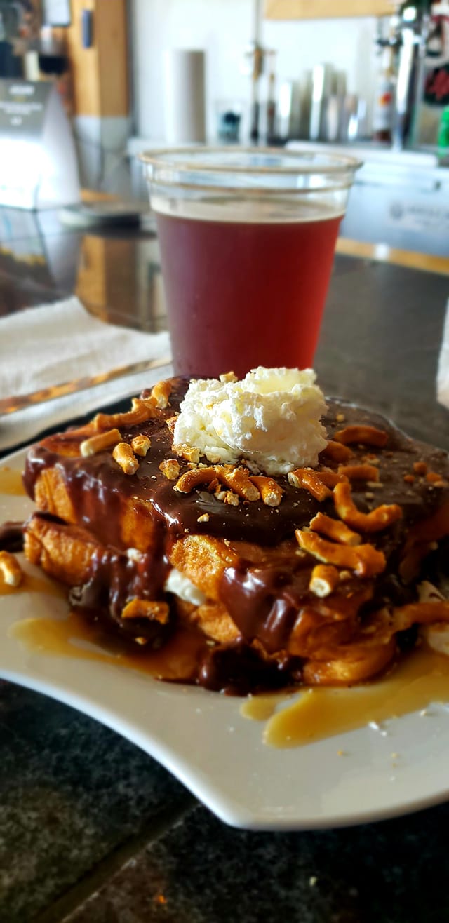 French toast covered in chocolate, broken pretzel pieces, and whipped cream. Served with a beer from Bascule Brewery.