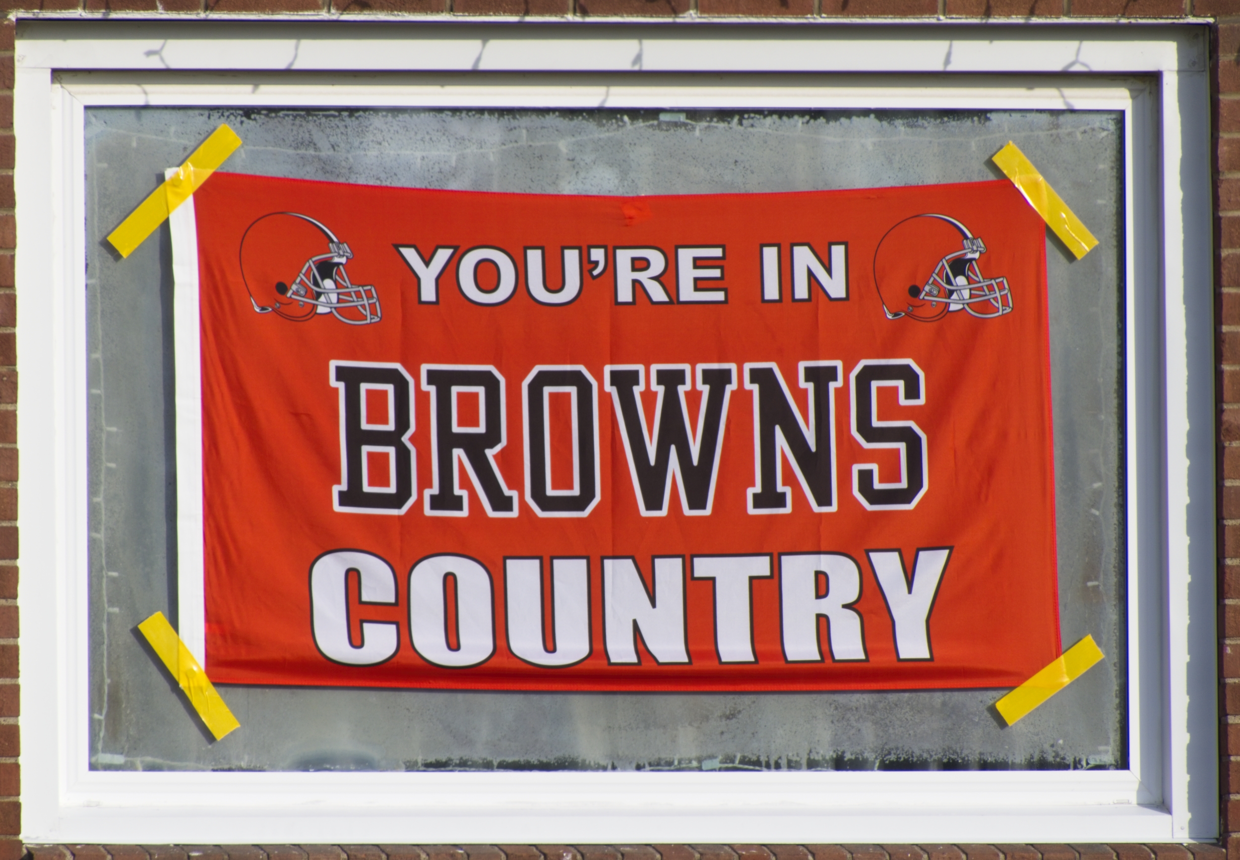 Orange flag reading "You're in Browns Country" taped to front window of a residence in South Lorain, OH