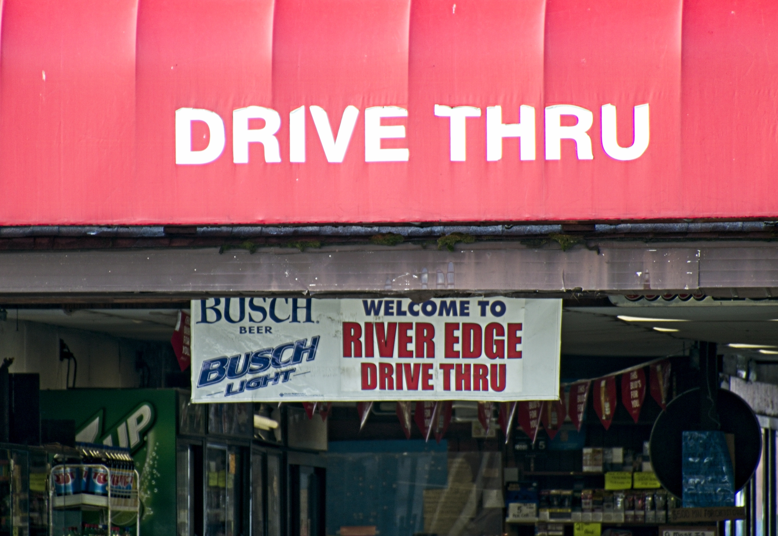 Red awning marked "Drive Thru" over entrance, banner sign inside welcoming patrons.