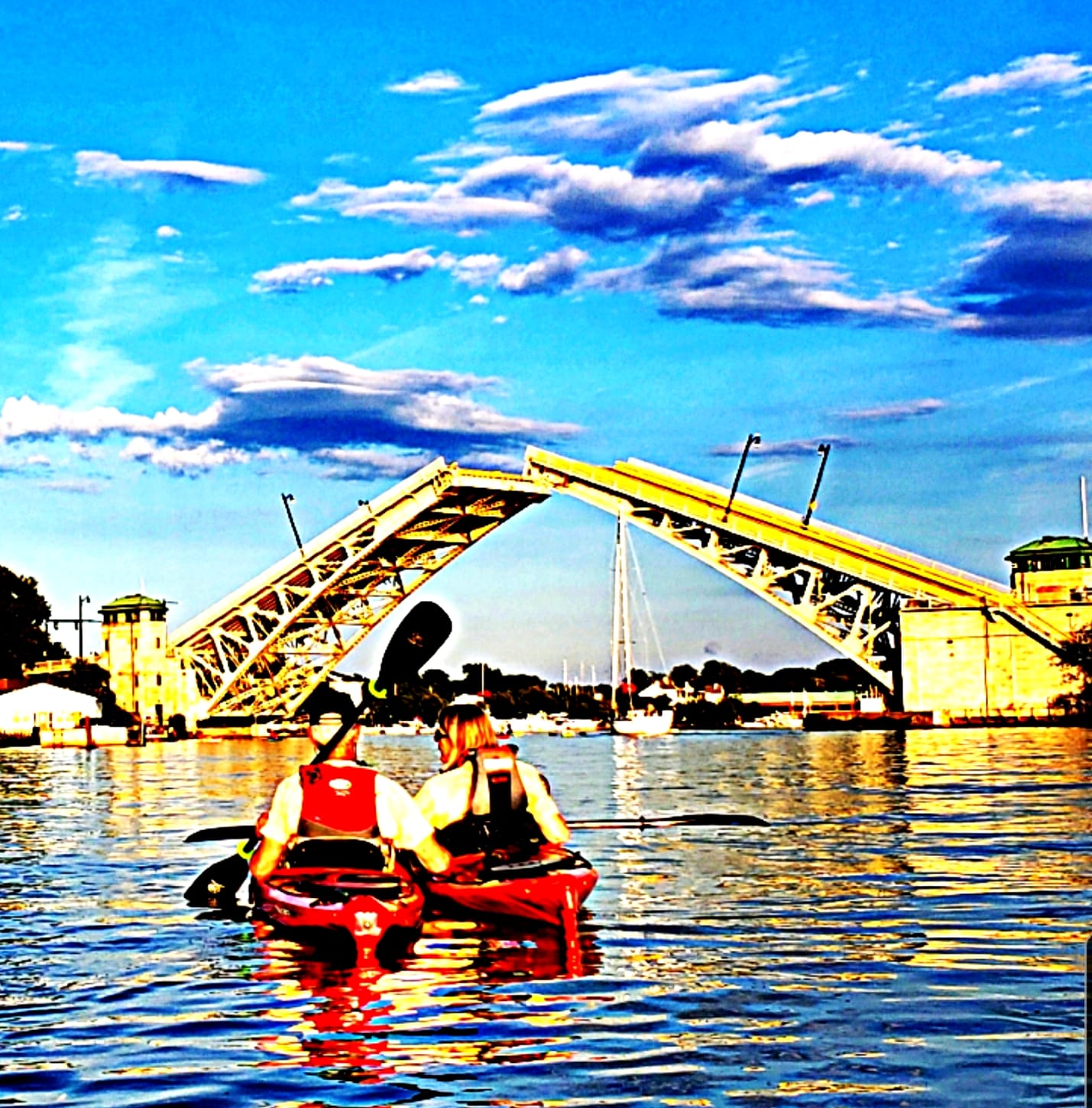 Heavily edited image of 2 kayakers in the river in front of a partially open drawbridge