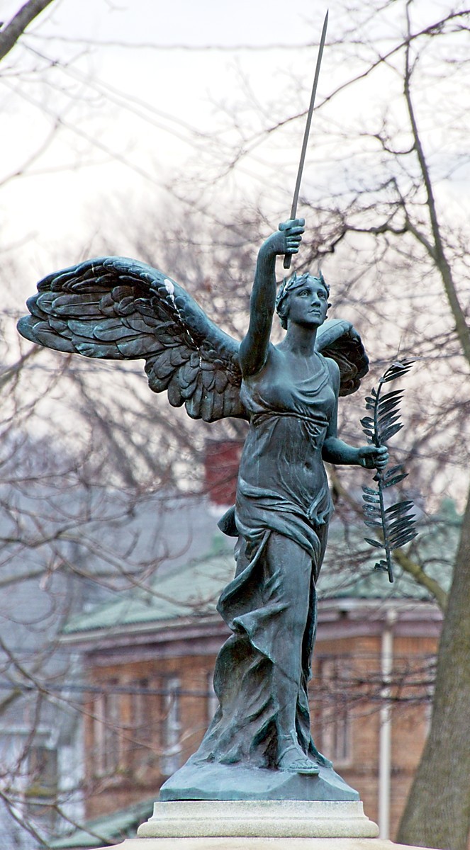 A statue representing the goddess Nike [Victory], bearing a palm frond in her left hand and raising a sword with her right. She's the centerpiece of a small triangular shaped park marked by a large white capital letter V on the corner.