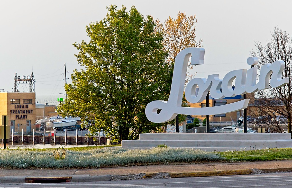 Photo of new Script Lorain sign with the sewage treatment plant in the background.